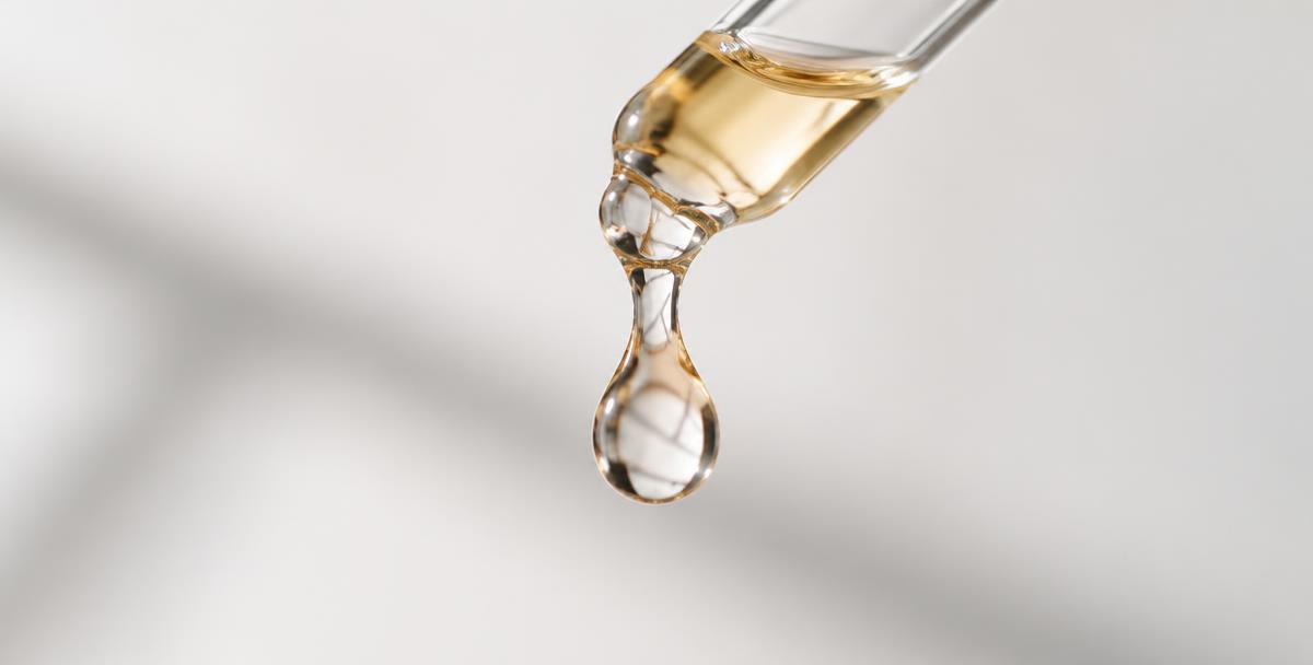 Close-up photograph of a single droplet forming at the tip of a glass dropper